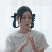 a woman with pigtails and a bow in her hair is making a funny face