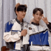 two young men are standing next to each other in a room and making a peace sign .