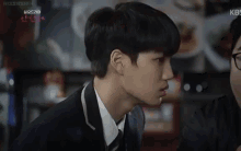 a young man in a suit and tie is talking to another man in a restaurant .