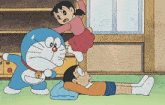 a cartoon of doraemon standing next to a girl and a boy laying on the floor