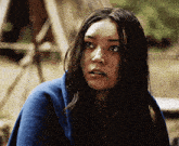 a woman wrapped in a blue blanket looks at the camera with a surprised look on her face