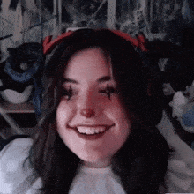 a woman wearing headphones and a clown nose is smiling .