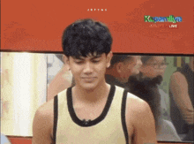 a man in a yellow tank top is standing in front of a red wall that says kapamilya