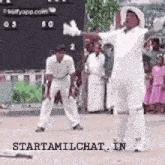 a cricket player is standing in front of a scoreboard with his arms outstretched .