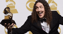 a man with long curly hair is holding a grammy