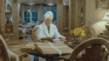a woman with a towel wrapped around her head is sitting at a table with a box on it