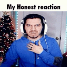 a man wearing headphones is making a funny face while standing in front of a christmas tree .