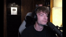 a man wearing headphones is sitting in front of a microphone in a room .