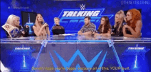 a group of people are sitting at a table in front of a talking sign
