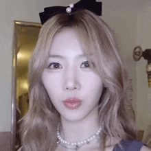 a close up of a woman wearing a pearl necklace and a bow in her hair