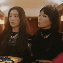 two women are sitting next to each other in front of a table with gifts .