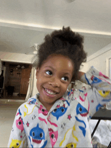 a little girl wearing a baby shark pajama top