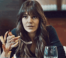 a woman sitting at a table with a glass of water and a fork in her hand