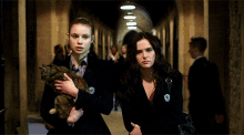 two women are walking down a hallway one holding a cat