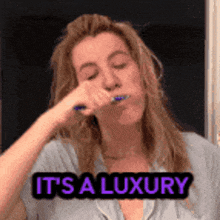 a woman brushing her teeth with the words it 's a luxury