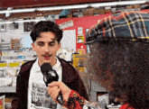 a man in a plaid hat is talking into a microphone in a store