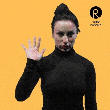 a woman in a black shirt is waving her hand in front of a yellow background that says teatr rozbark on it