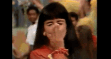 a woman is covering her nose with her hand in a crowd of people .