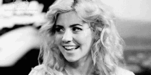 a black and white photo of a woman smiling with her eyes closed .