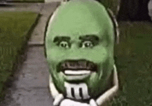 a cartoon character with a green face and a mustache is holding a m & ms candy .