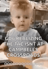 a baby is sitting at a table and making a funny face with a caption .