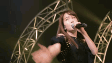 a woman singing into a microphone in front of a circular structure