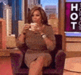 a woman is sitting in a chair with a cup of coffee in her hand .