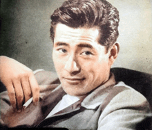 a man in a suit is smoking a cigarette and smiling