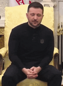 a man is sitting in a chair with his eyes closed and a shirt that says big on it
