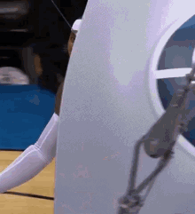 a woman in a white costume is standing on a basketball court next to a white wall .