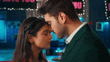 a man and woman are kissing in front of a sign that says " love you "