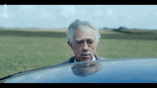 a man with gray hair and a mustache looks out of a car window