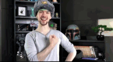 a man wearing a russian hat is standing in front of a shelf with a boba fett helmet on it