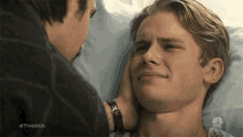 a man is comforting another man in a hospital bed .