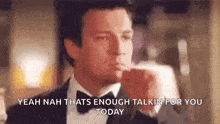a man in a tuxedo and bow tie is thinking about something while holding his hand to his chin .
