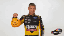 a man wearing a rush truck centers shirt holds a pumpkin