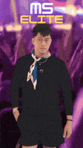 a man wearing glasses and a scarf is standing in front of a ms elite sign
