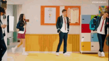 a group of students are dancing in a hallway in a classroom .