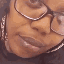 a close up of a woman 's face wearing glasses and earrings .