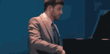 a man in a suit and tie is playing the piano