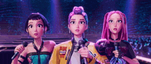 three cartoon girls are singing into microphones on a stage . one of the girls is wearing a yellow jacket that says hollywood
