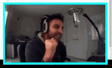 a man wearing headphones is sitting in front of a microphone and making a funny face .