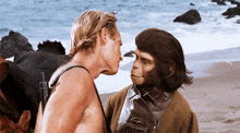 a man and a monkey are standing on a beach and the monkey is wearing a jacket that says gmc on it