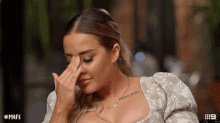 a woman with a tattoo on her chest is covering her face with her hand