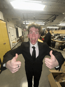 a young man in a suit and tie is giving a thumbs up