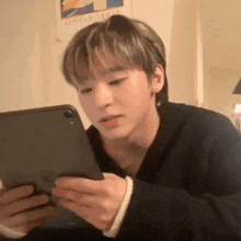 a young man is looking at a tablet computer while sitting at a table .