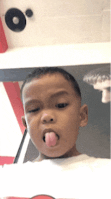 a young boy sticking his tongue out in front of a mirror