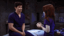 a man and a woman are standing next to each other and the woman is wearing a purple scrub top