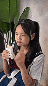 a girl in a school uniform is eating a sandwich while holding a bag .