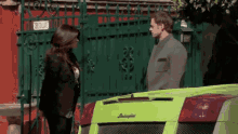 a man and a woman are standing next to a green lamborghini